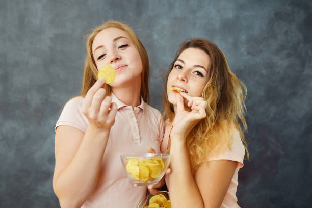 istock Two young women greedily eating potato chips 1013735076