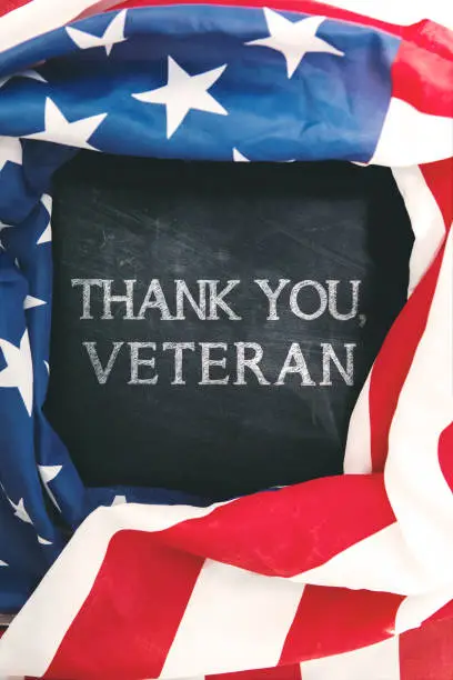 Top view of American flag shaped a frame with text of thank you, veteran on the chalkboard