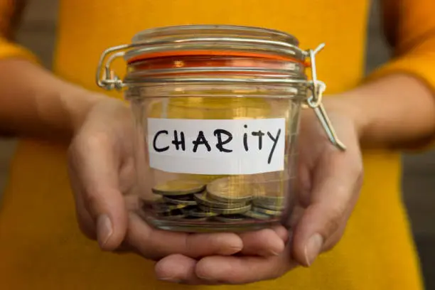 Woman collecting money for charity and holds jar with coins.