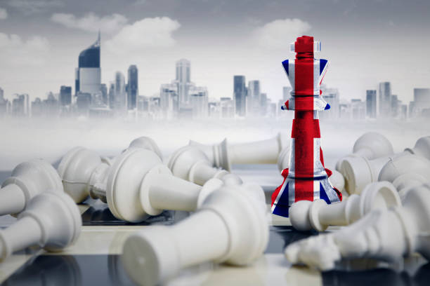 Picture of England flag on a chess king near fallen white chess pieces. Shot with modern city