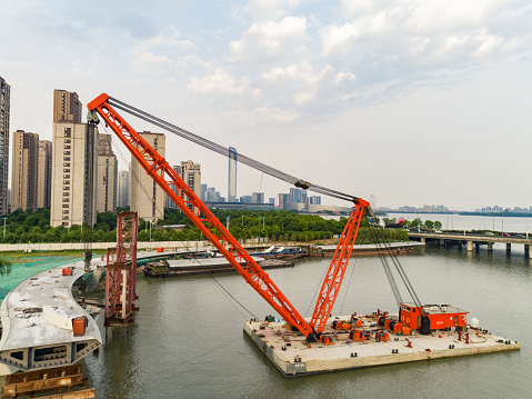 Aerial view of floating crane, pedestrian bridge over river construction