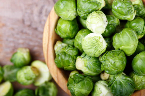 istock raw brussels sprouts on a wooden background. 1013766494