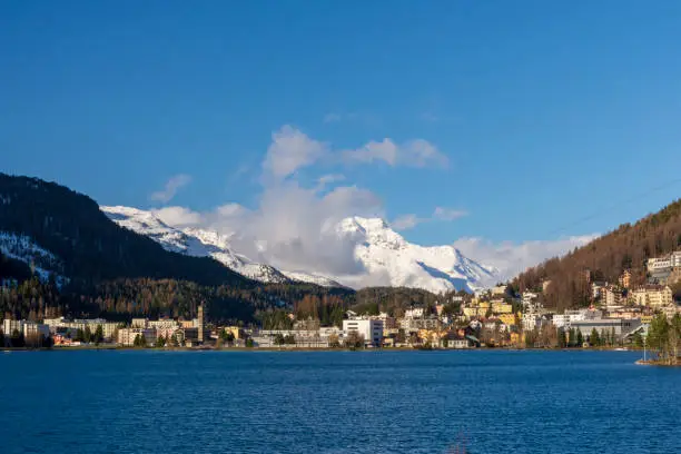 View over St. Moritzersee to St.Moritz town with snowy alps and a blue sky in background, picture from Switzerland.