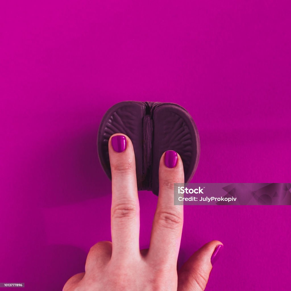 Vagina concept on purple background Vagina symbol. Two fingers on chocolate orange on purple background. Minimalism concept. Top view, copy space, square Vagina Stock Photo