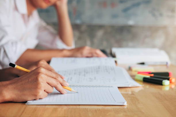 istock High school or college student group catching up workbook and learning tutoring in classroom and reading, doing homework and lesson practice preparing exam 1013792026