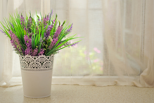 Beautiful artificial flowers with lavender on the window