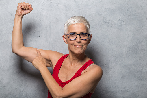 Woman showing her muscles and pointing finger at it