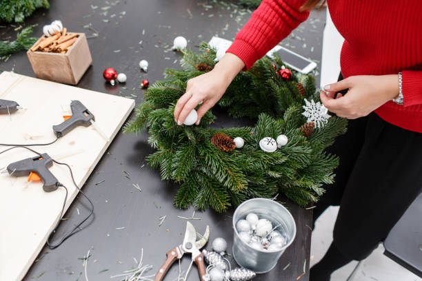 istock A woman decorates a Christmas wreath. Hands close-up. Master class on making decorative ornaments. Christmas decor with their own hands. The new year celebration. Flower shop 1013805870