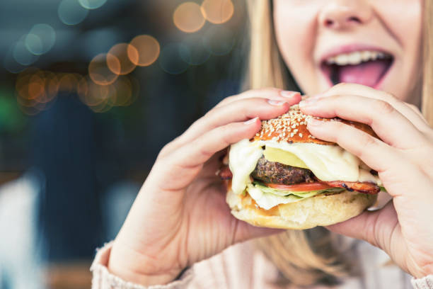 istock Girl about to bite into huge cheeseburger 1013811104