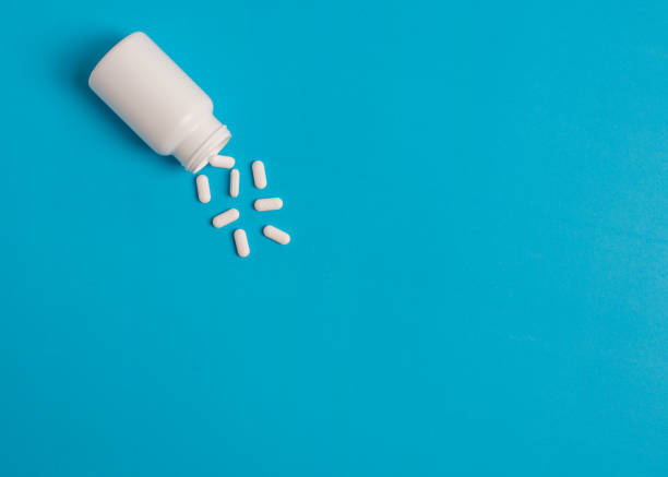 istock white pills and pill bottle on blue sky background. 1013813654