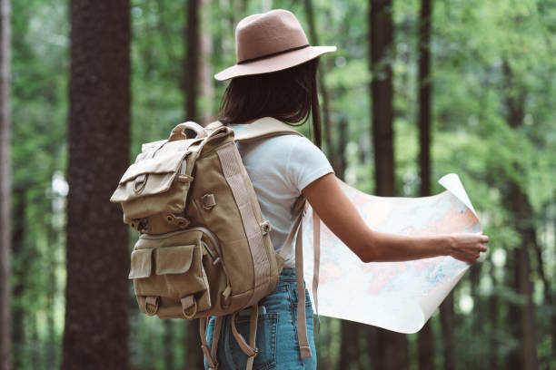 istock Traveler hipster woman in forest with backpack searching direction on map 1013814200