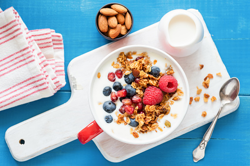 Granola with yogurt, blueberries, raspberries and pomegranate seeds in a bowl, top view. Healthy eating, healthy lifestyle, healthy breakfast food