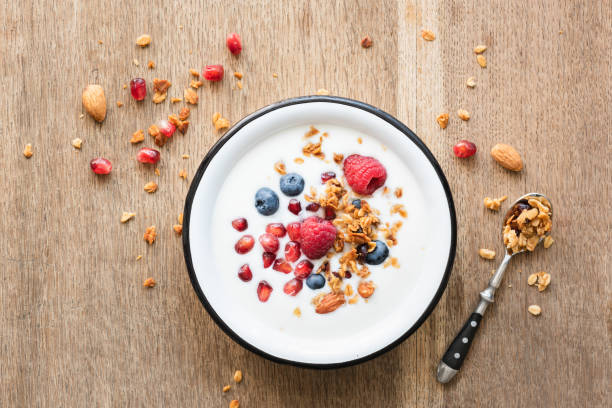 Greek yogurt with granola and berries on wooden table Greek yogurt with honey granola, pomegranate seeds, blueberries and raspberries on wooden table. Top view greek yogurt photos stock pictures, royalty-free photos & images