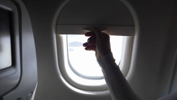 istock CLOSE UP: Unknown person pulls up airplane window shade and reveals blue sky. 1013829482