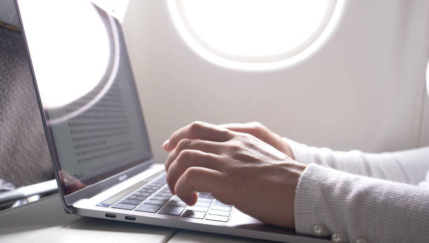 istock CLOSE UP: Female's fingers type on sleek laptop keyboard during a long flight. 1013829504