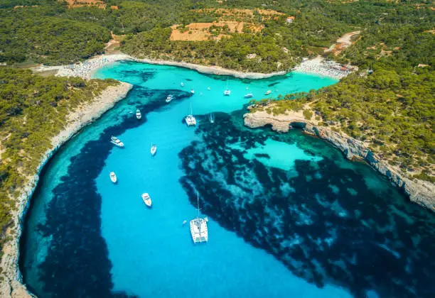 Photo of Aerial view of boats, luxury yachts and transparent sea at sunny day in Mallorca, Spain. Colorful summer landscape with marina bay, blue water, sandy beach, sky. Balearic islands. Top view. Travel