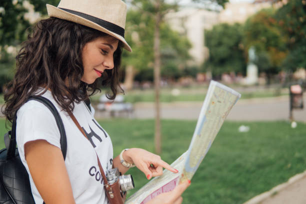 istock Young woman with the camera looking at touristic map in her hands 1013847298