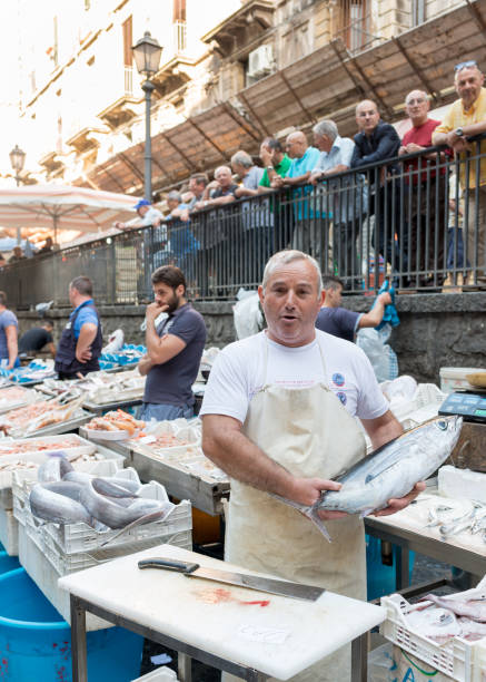 ein anbieter ist showing off seinen fisch auf dem fischmarkt von catania, sizilien, italien - personal land vehicle audio stock-fotos und bilder