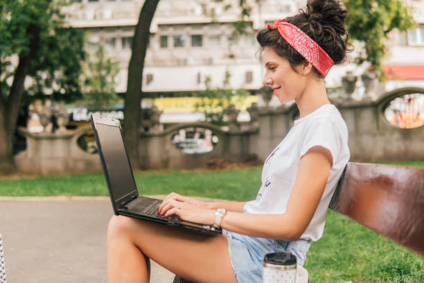 istock Young woman working on laptop at the park 1013850736