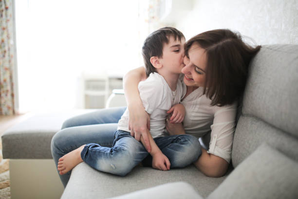 istock beautiful brunette mom and son hugging on sofa 1013853542