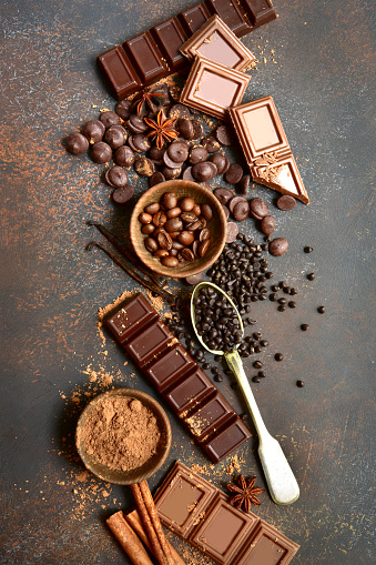 Ingredients for making chocolate cake or candy : chocolate chips, bar and spices on a dark slate, stone or concrete background.Top view with copy space.