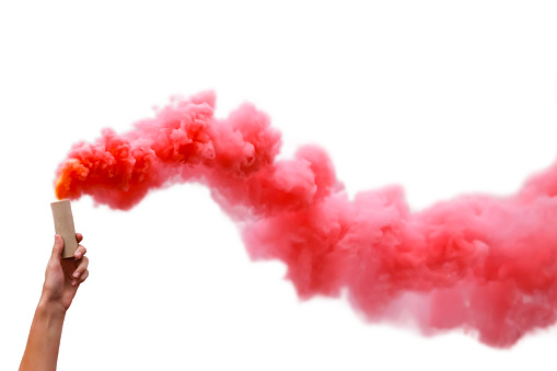 Human hand holding smoke bombs with red smoke, isolated on white background.