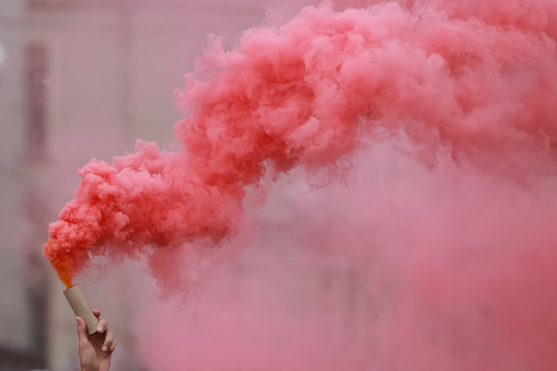 A man holding a hand flare with red smoke.