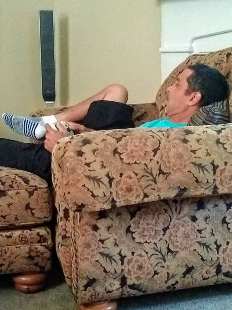This is a relaxed man. He has a game controller in his hands, playing video games.