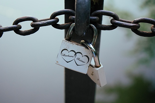 A heart-shaped lock on the chain above the lake on the bridge symbolizes a new family.