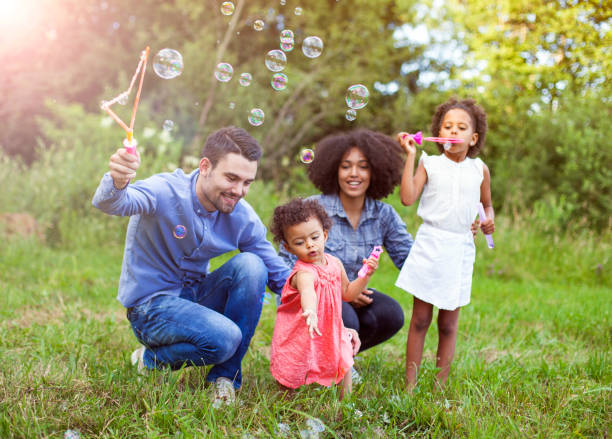 istock Happy family playing soap bubbles in park. 1013911378