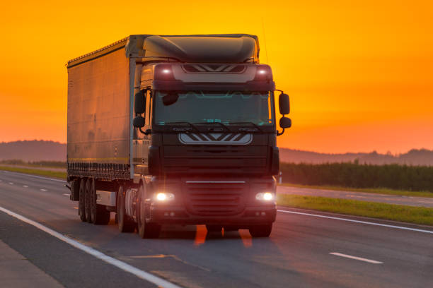 istock logistics truck on the highway at dawn, orange sky 1013913514