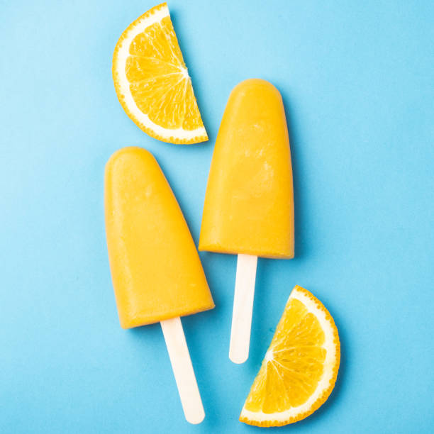 istock Orange popsicles with juice on a blue background. Ice pops, flat lay, top view 1013921814