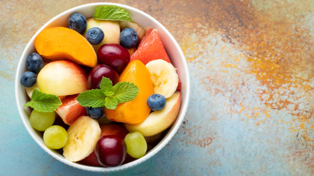 istock Bowl of healthy fresh fruit salad on a blue rusty background. Top view with copy space. Flat lay 1013921856