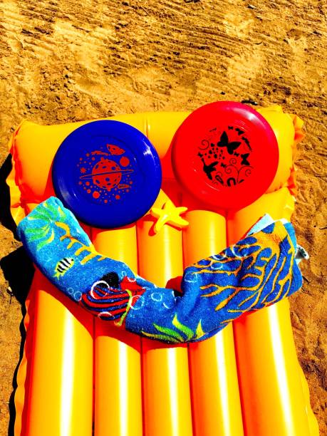 Beach Smile Orange raft on Lake Michigan beach in Gladstone, Michigan. The raft has two frisbees, a plastic starfish, and a towel that form a smiling face on the raft gladstone michigan stock pictures, royalty-free photos & images