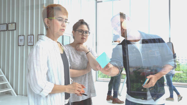 istock Multi Ethnic Creative team brainstorming in smart casual wear having a meeting while standing behind the glass wall at the office 1013952248