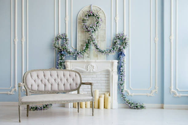 istock Classic gray sofa in a luxurious white room. artificial fireplace. on the fireplace. the room is decorated with flowers 1013994330