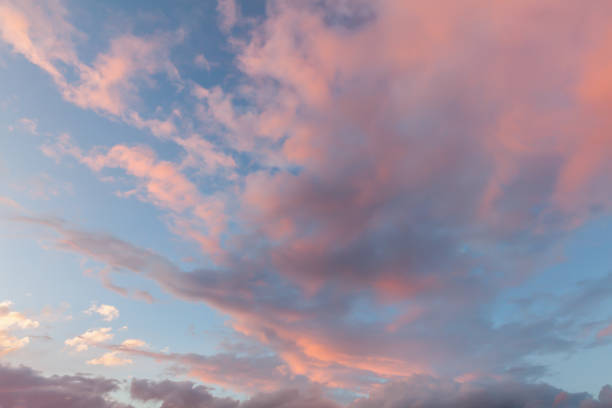 Beautiful clouds and blue sky background at sunset with pink and purple tones over England UK. Cloudscape and skyscape backdrop