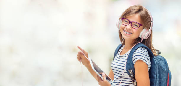 Portrait of modern happy teen school girl with dental braces glasses bag backpack headphones and tablet. Portrait of modern happy teen school girl with dental braces glasses bag backpack headphones and tablet. braces stock pictures, royalty-free photos & images