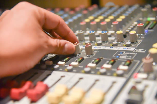 istock close-up hands of sound engineer adjusting audio mixer controller for live music and studio equipment. This is a quality audio system for professionals. vintage tone & effect light in control room. 1014031416