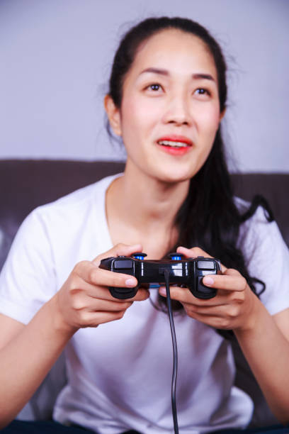 istock woman using joystick controller playing video game on sofa in living room 1014032036