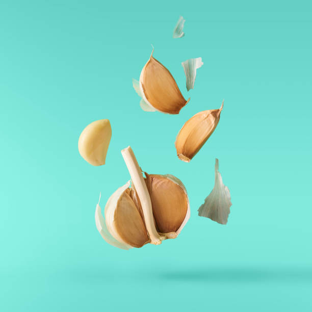 Garlic falling in air on turquoise background. stock photo