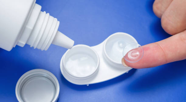 istock Woman's hand with contact lens, storage case and bottle with solution for all types of soft contact lenses. 1014044296