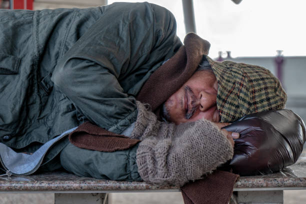 istock Homeless male sleeping on stone bench at train terminal 1014056564