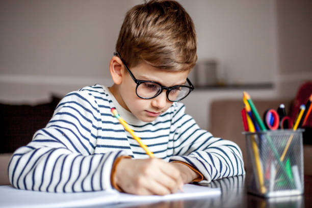 istock Cute 7 years old boy doing homemork 1014060582