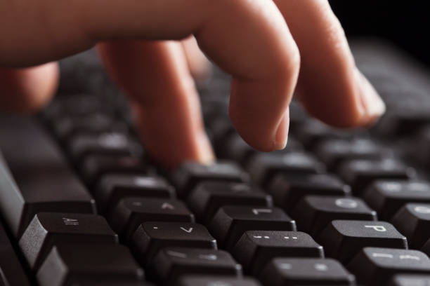 A woman's hands typing on a computer's keyboard in close-up.
