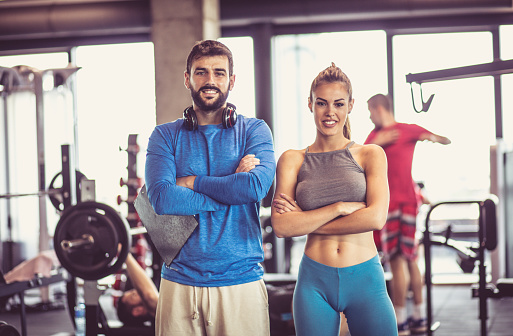 Portrait of smiling man and woman in gym.