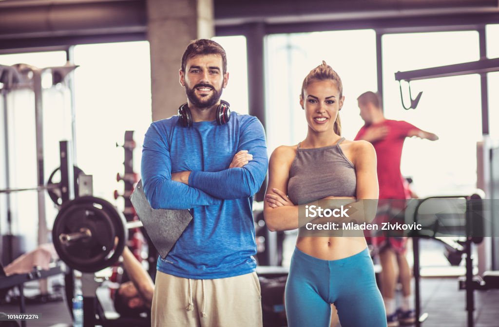Portrait of smiling man and woman in gym. Fitness Instructor Stock Photo