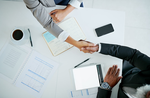 High angle shot of two businesspeople shaking hands during meeting in an office