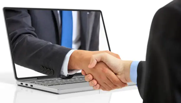 Photo of 3d rendering men shaking hands through a laptop screen