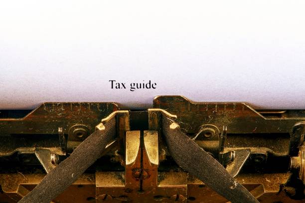 istock Closeup on vintage typewriter. Front focus on letters making TAX GUIDE text. Business concept image with retro office tool 1014086276